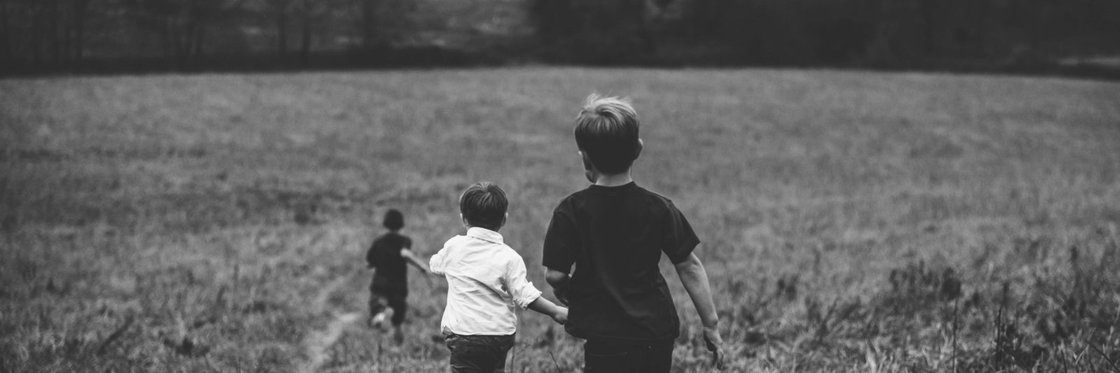 black and whit eimage of three young boys running through a field